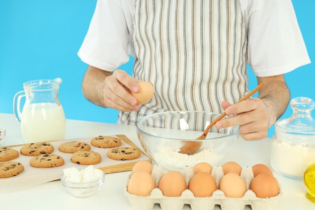 Concept van het koken van koekjes met jonge man tegen blauwe achtergrond