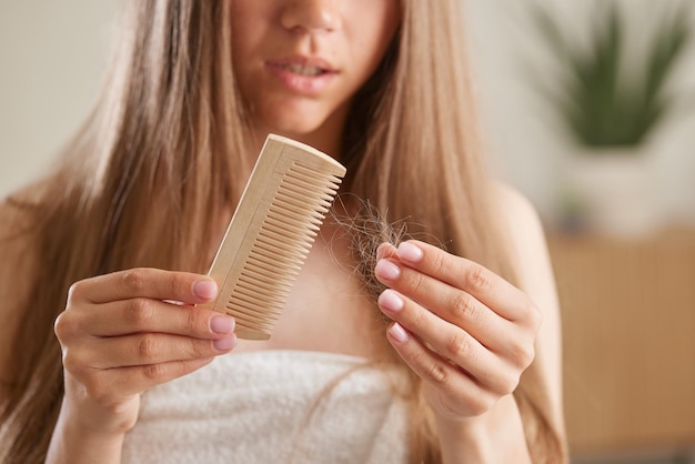 concept van het probleem van haaruitval Geschokte vrouw kijkt naar veel haar verloren in haar hand en kam