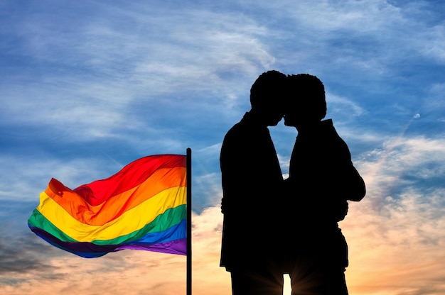 Concept van homoseksuelen. Silhouet gelukkige homo zoenen tegen de avondlucht en een regenboogvlag