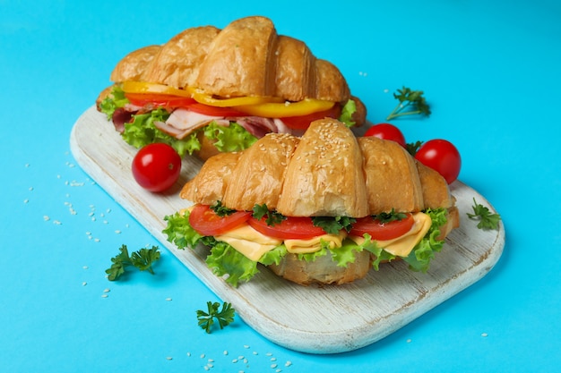 Concept van lekker eten met croissantsandwiches op blauw, close-up