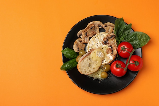 Concept van lekker eten met gegrilde camembert op oranje achtergrond.