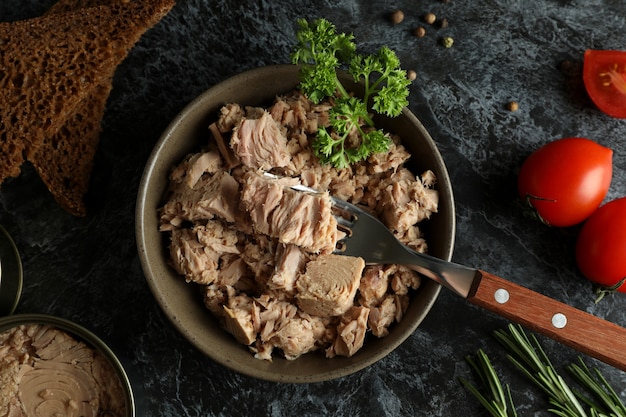 Concept van lekker eten met ingeblikte tonijn op zwarte rokerige achtergrond