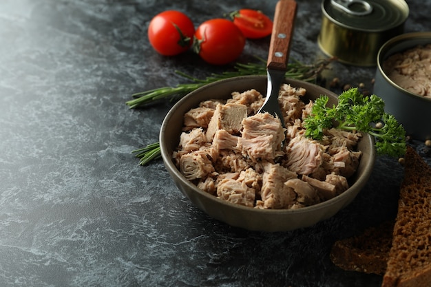 Concept van lekker eten met ingeblikte tonijn op zwarte rokerige achtergrond