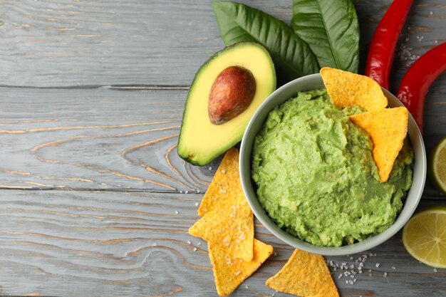 Concept van lekker eten met kom guacamole op houten achtergrond, ruimte voor tekst