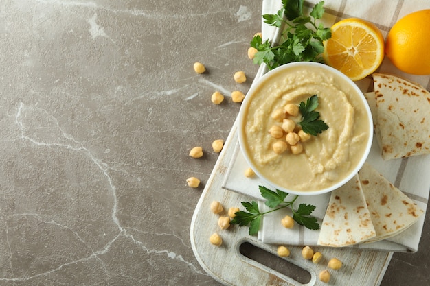 Concept van lekker eten met kom hummus op grijze ondergrond