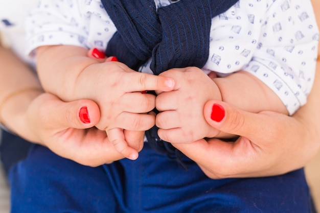 Concept van liefde en familie. Handen van moeder en baby close-up.