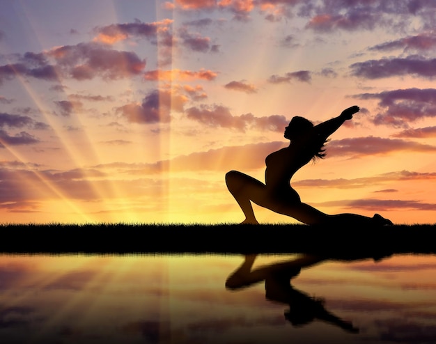 Foto concept van meditatie en ontspanning. silhouet van een meisje dat yoga beoefent bij zonsondergang en reflectie in water