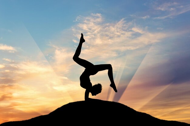 Concept van meditatie en ontspanning. Silhouet van een meisje dat yogaoefening beoefent op de zonsondergangachtergrond