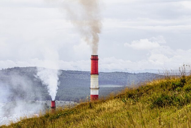 Foto concept van milieuverontreinigende leidingen met rook op achtergrond van bos en berg