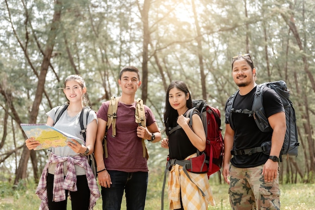 Concept van natuurtoerisme en trekking, een groep van vier Aziatische mannelijke en vrouwelijke backpackers. Kijk recht in de camera Een boswandeling plannen.