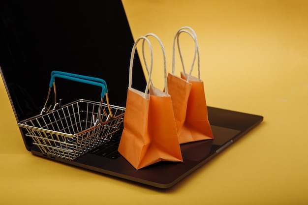 Concept van online winkelen. Oranje zakken en boodschappenwagentje op laptop