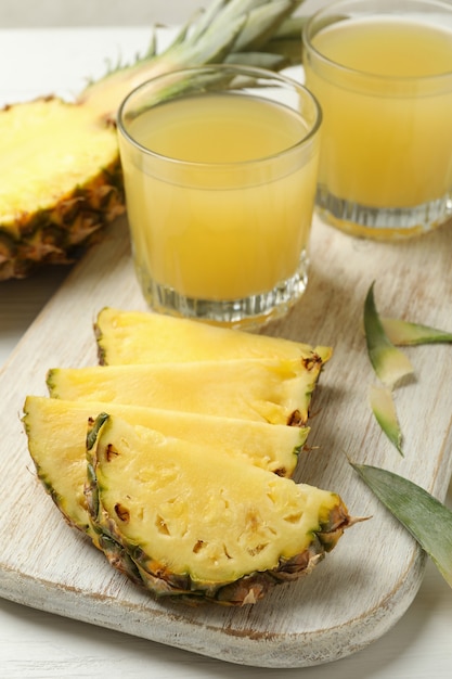 Concept van ontbijt met ananas en glazen met sap op houten tafel