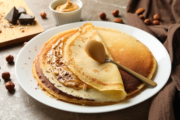 Concept van ontbijt met pannenkoeken met pindakaas en noten op grijze tafel