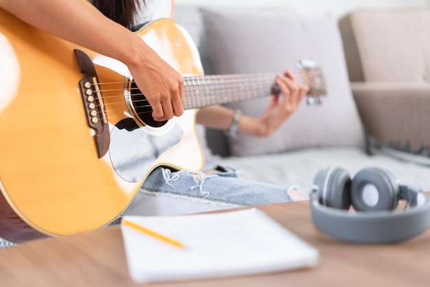 Concept van ontspanning met muziek jonge Aziatische vrouw die muziek speelt met teksten en akoestische gitaar