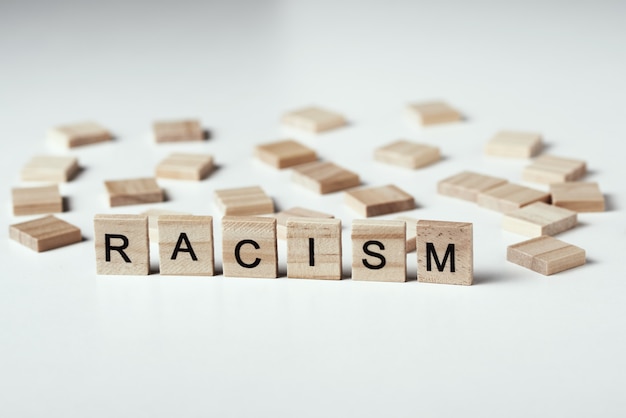 Concept van racisme en misverstand tussen mensen, vooroordelen en discriminatie. houten blok met woord racisme op de witte backround