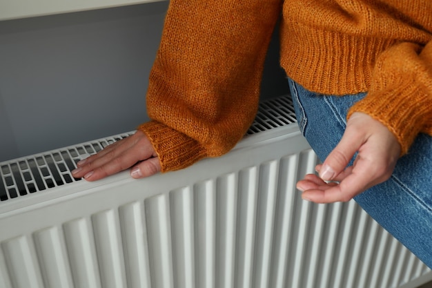 Foto concept van stookseizoen met meisje zittend op radiator.