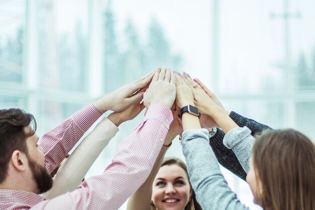 Concept van teamwerkvriendelijk business team dat in een cirkel staat en hun handen opsteekt