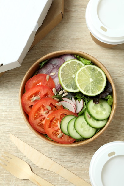 Concept van voedselbezorging met groentesalade op houten achtergrond