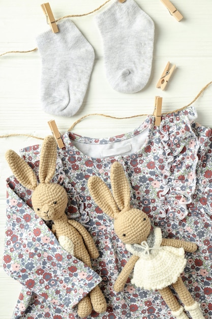 Concept van vrouwelijke babykleding op witte houten achtergrond.