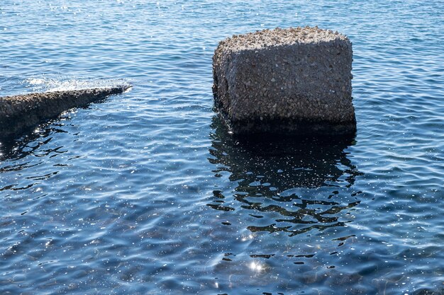 Concept van zeeverontreiniging Schuim tussen kaderotsen op het glinsterende zonnige wateroppervlak