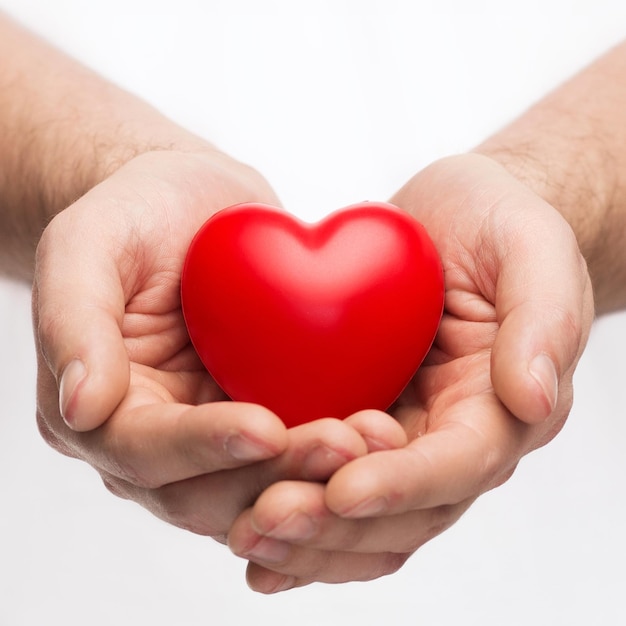 concept voor gezondheid, geneeskunde en liefdadigheid - close-up van mannelijke handen met klein rood hart