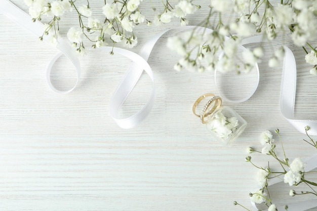 Concetto di accessori da sposa con fedi nuziali su fondo di legno bianco