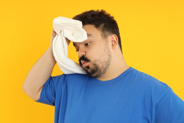 Concept of weight loss fat guy with towel on yellow background