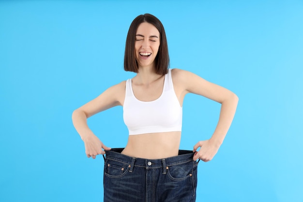 concept of weight loss with young slim woman on blue background