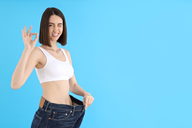 Concept of weight loss young woman on blue background