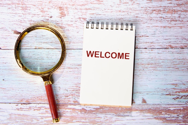 The concept of the welcome text write in a notebook on the boards next to the magnifying glass