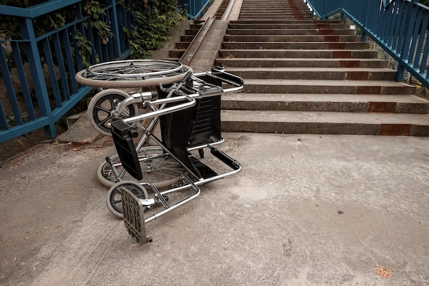 The concept of a wheelchair on the stairs turned over, disabled, full life, paralyzed. Problems for the disabled person.