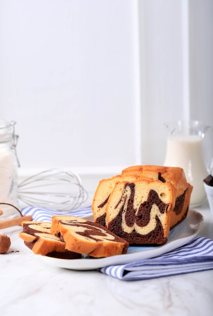 Concept White Background Bakery, Loaf Marble Cake Slice on Stone Black Plate with Ingredient at Background