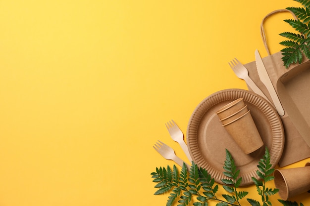 Concept with eco - friendly tableware and plant on yellow, copy space