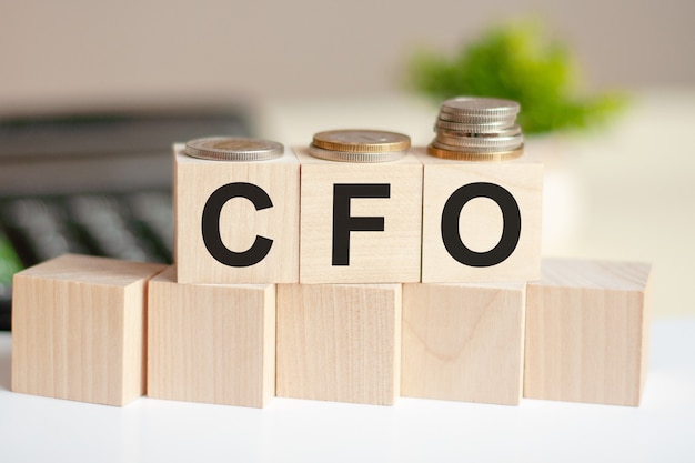 Concept woorden CFO op houten blokken op mooie muur van dollarbiljetten. Het woord CFO op houten kubussen met munten en rekenmachine aan de muur. bedrijfsconcept. CFO - Chief Financial Officer