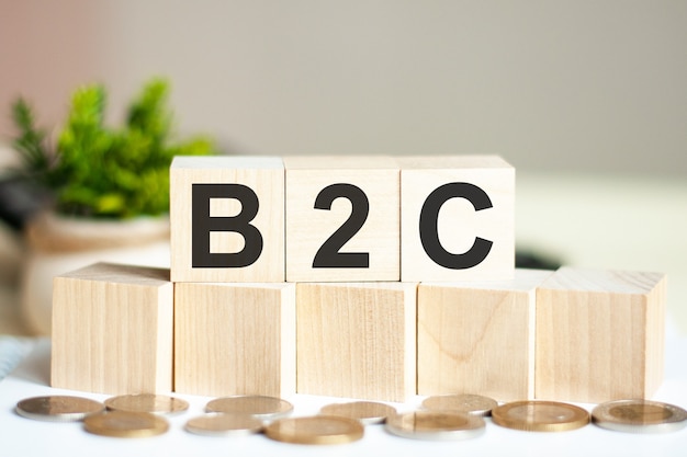 美しい壁の木製ブロックのコンセプトワードB2C。壁にコインが付いた木製の立方体のB2Cという言葉。ビジネスコンセプト。 B2C-企業から消費者へ