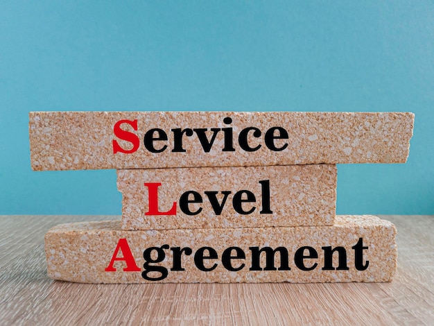 Concept words SLA service level agreement on brick blocks Beautiful blue background wooden table Business SLA service level agreement concept