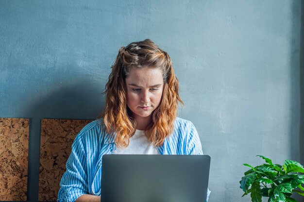 concept work from home freelance remote worker girl sitting on bed with laptop and working smiling