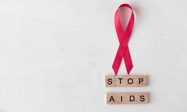 Concept for World AIDS Day. Red ribbon near wooden letters. Stop AIDS words. Baner. Copy space.