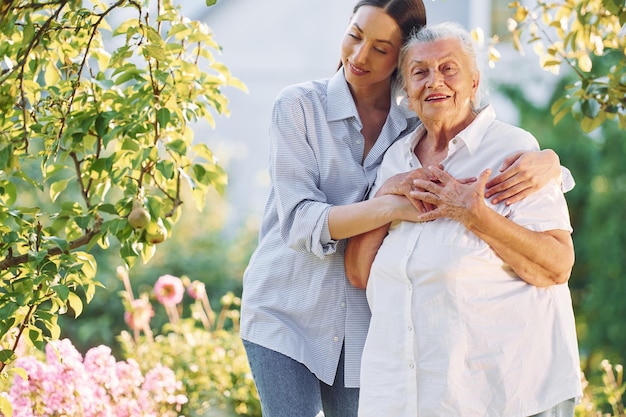 Conceptie van liefde voor een ouder Jonge vrouw is met haar senior moeder in de tuin