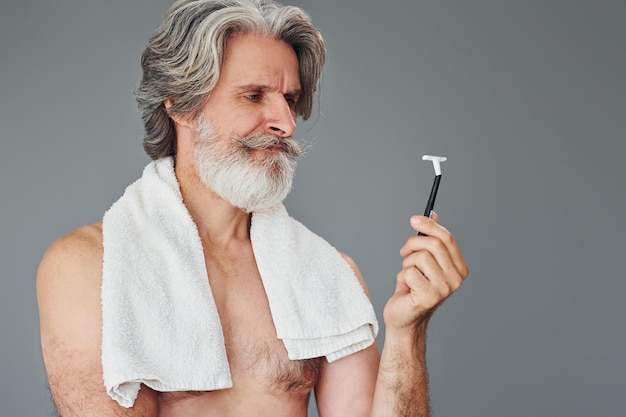 Foto concezione della rasatura l'uomo anziano moderno ed elegante con i capelli grigi e la barba è al chiuso