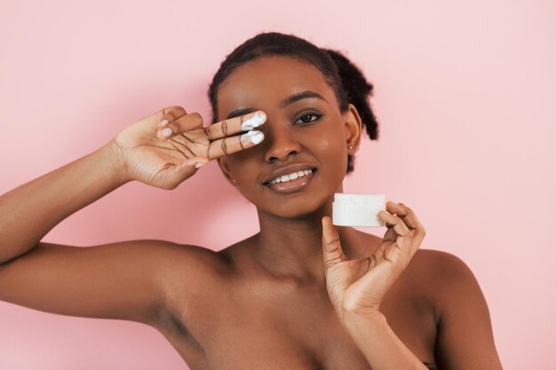 Conception of skin care portrait of young african american
woman that is against pink background