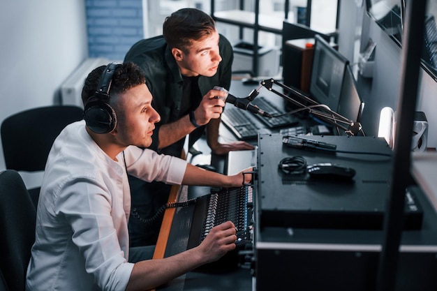 팀워크의 개념 라디오 스튜디오에서 실내에 있는 두 남자는 방송으로 바쁘다