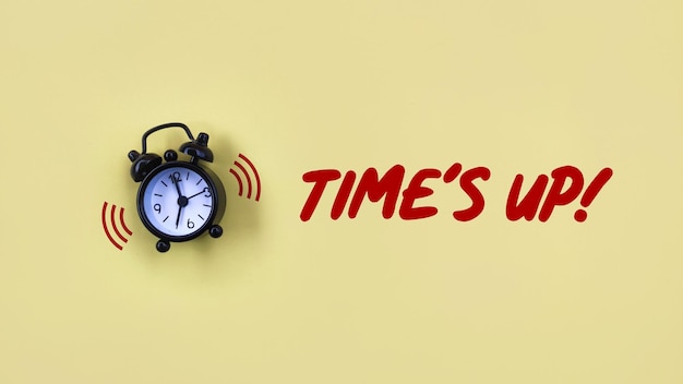 黄色の背景に TIMES UPというテキストが描かれた概念的な黒い目覚まし時計
