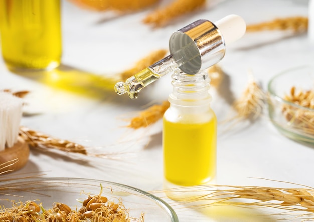 Una composizione concettuale di olio essenziale di grano una spazzola da bagno e germe di grano su un tavolo di marmo bottiglia di olio per il corpo con contagocce olio di siero di grano per la cura della pelle e dei capelli selfcare spa e benessere