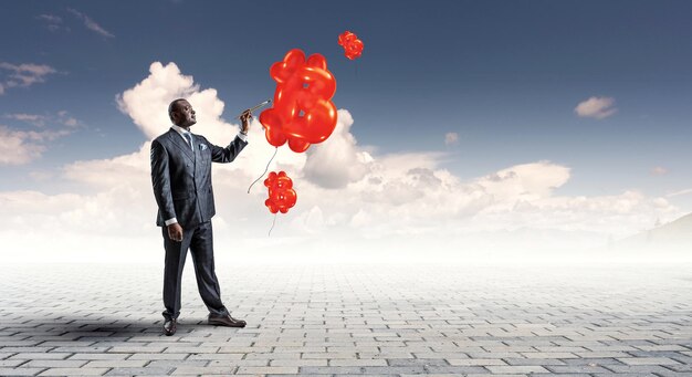 Conceptual image of ambitious and creative businessman in black suit holding paintbrush in hand