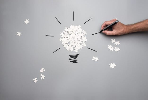 Conceptual image of business vision and idea with a pile of white scattered puzzle pieces forming a light bulb