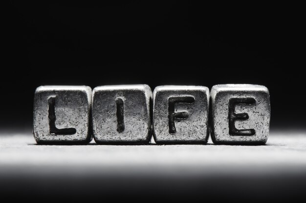 Photo conceptual inscription life on metal cubes on a black gray background close-up isolated