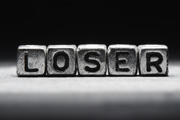 Conceptual inscription loser on metal cubes on a black gray background close-up isolated