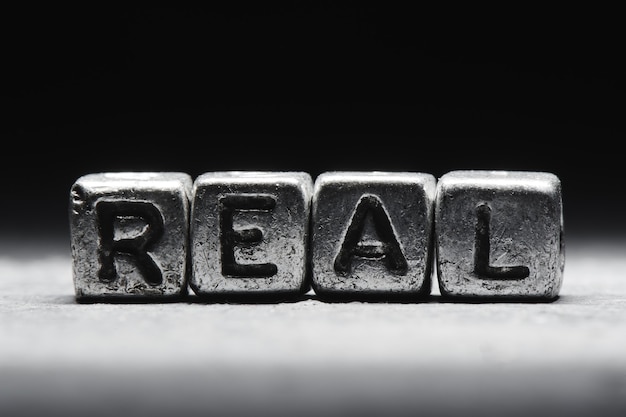 Conceptual inscription real on metal cubes on a black gray background close-up isolated