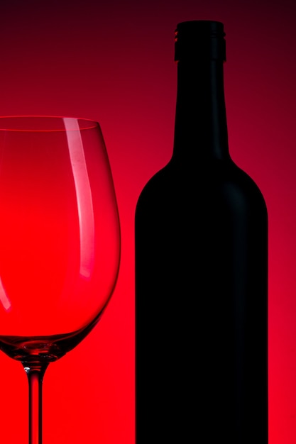 Conceptual photo of wine bottle and glass on red background.